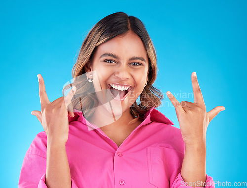 Image of Happy, portrait and woman with rocker hands in studio for freedom, fun and positive attitude on blue background. smile, face and female with rockstar emoji, sign or punk gesture, good mood or vibes