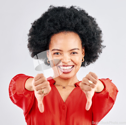 Image of Portrait, smile and thumbs down with a black woman in studio on a white background to deny or reject. Face, negative and a happy young female person posing to gesture no with a disagreement emoji