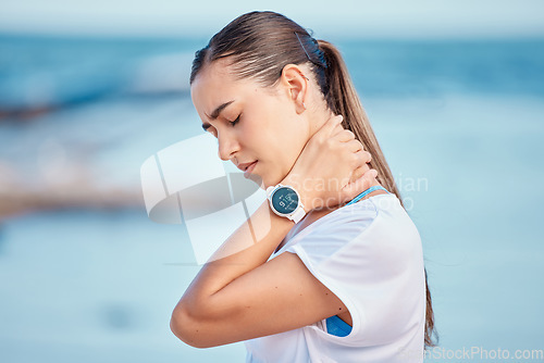 Image of Outdoor, woman and shoulder or neck pain from exercise at the beach, ocean or workout to relax muscle, stress and strain. Massage, injury and training for sports, fitness or athlete in burnout