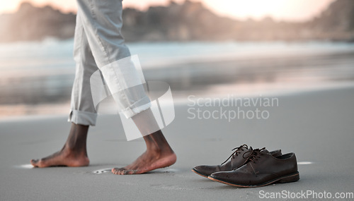 Image of Shoes, feet and beach for business man, freedom and sunset to relax in nature by water after work. Person, ground and ocean with barefoot adventure for holiday, outdoor and steps on sand at dusk