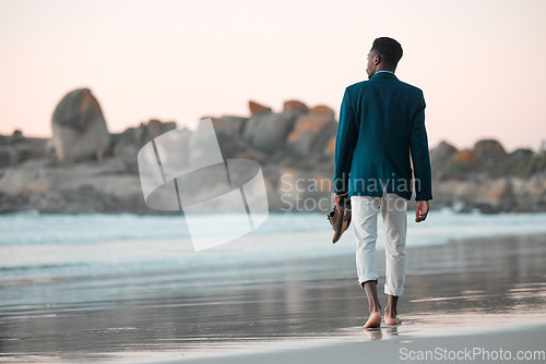 Image of Walking, beach and back of business man for journey on holiday, vacation and freedom by ocean. Professional, travel and male entrepreneur barefoot for calm, peace and relaxing in nature at sunset