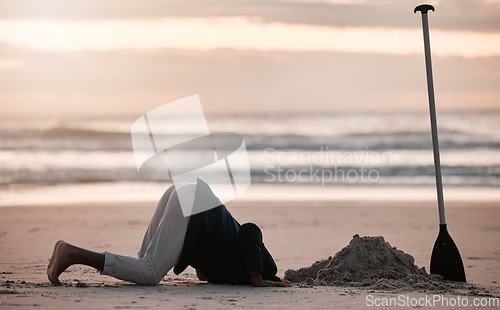 Image of Digging hole, search and a man on the beach for a vacation, treasure hunt or check underground. Nature, travel and a person with a shovel at the ocean during sunset or sunrise and playing in the sand