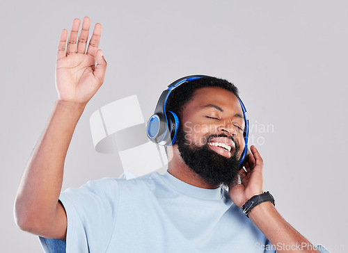 Image of Headphones, sing and man in a studio with music, playlist or album while dancing with energy. Happy, smile and young African male model listening to a song or radio online isolated by gray background