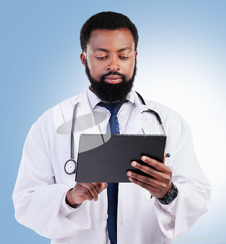 Image of Healthcare, tablet and a black man doctor in studio on a blue background for cardiology research. Medical, technology and innovation with a male medicine professional searching for information online