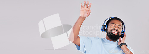 Image of Headphones, mockup and young man in a studio listening to music, playlist or album while dancing. Happy, smile and African male model streaming a song or radio by a gray background with mock up space