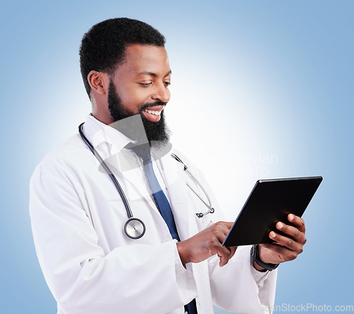 Image of Healthcare, tablet and a black man doctor on a blue background in studio for cardiology research. Medical, technology and innovation with a male medicine professional reading information online