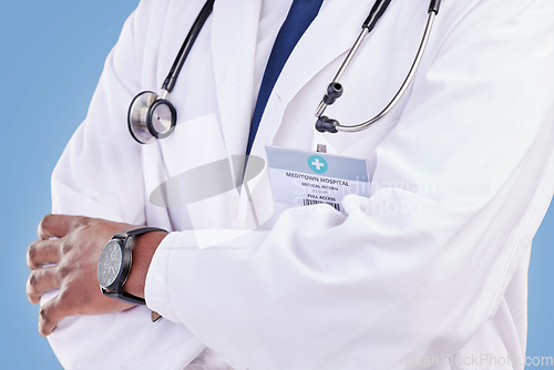Image of Doctor, stethoscope and arms crossed in studio with a medical expert or healthcare worker on blue background. Surgeon, hands and confidence in medicine or pharmaceutical research in hospital