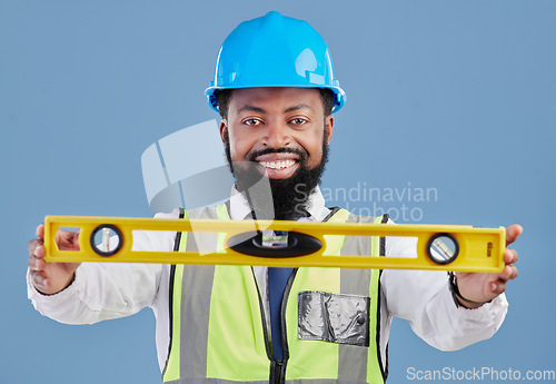 Image of Happy black man, portrait and architect with level for measuring in construction against a blue studio background. African male person, engineer or contractor smile holding tool for measurements