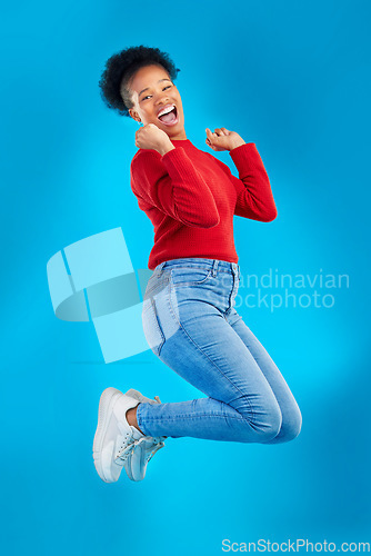 Image of Excited, jump and woman portrait with winner, deal and smile in a studio. Wow, energy and up in the air with female person and blue background with celebration for sale announcement and big news