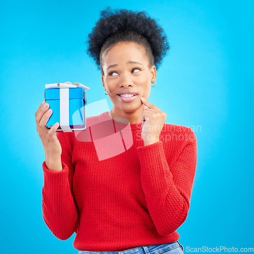 Image of Thinking, winner and black woman with a present, box and celebration against a blue studio background. Female person, doubt or model with a gift, giveaway product or package with surprise and curious