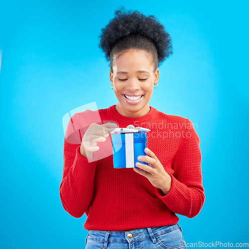 Image of Smile, birthday and a black woman with a gift on a blue background for happiness or a surprise. Holding, box and a young African girl with a present for a celebration isolated on a studio backdrop