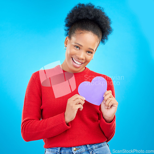 Image of Woman, portrait and heart cut out with a smile for love and valentines day in studio. African female person, blue background and romance emoji icon for kindness with a young happy model and paper