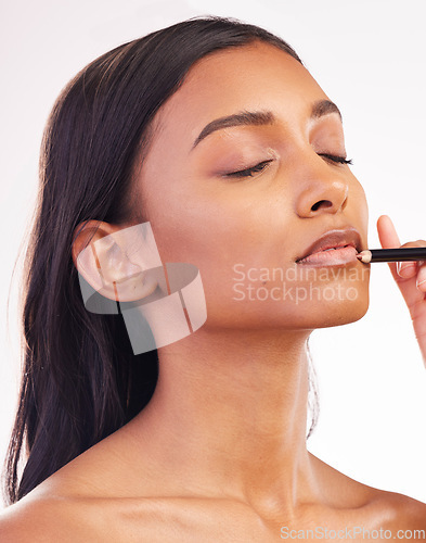 Image of Beauty, makeup and pencil on face of woman in studio for cosmetics, lip liner and product. Salon, self care and glow with female model on white background for application, lipstick and facial