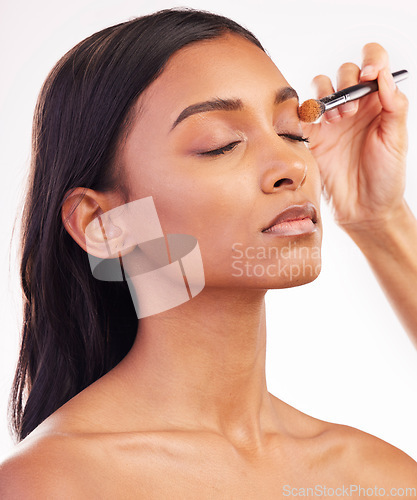 Image of Beauty, makeup and brush on face of woman in studio for cosmetics, foundation and eyeshadow. Salon, self care and glow with female model on white background for application, powder and facial