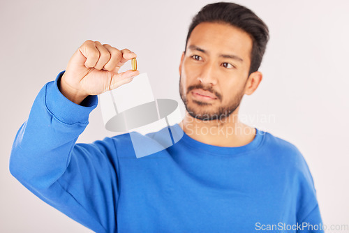 Image of Healthcare, showing and a man with a pill on a studio background for a virus, covid or supplement. Sick, medical and an Asian person with a tablet, medication or vitamin c medicine for wellness