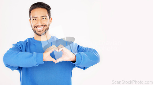 Image of Portrait, heart and hands of man in studio, white background and care for kindness on mockup space. Happy asian male model with finger shape for love icon, thank you and emoji in support of freedom