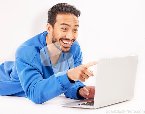 Image of Surprise, laptop and man pointing on studio floor isolated on a white background. Computer, happy and person on ground for social media, streaming movie or film, video or show on internet with tech