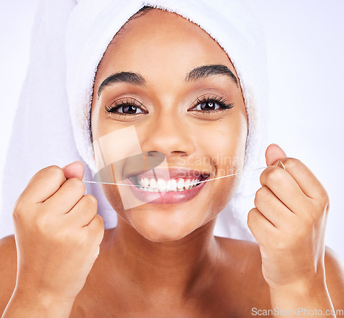 Image of Dental floss, teeth and face of a woman for health and wellness in studio. Portrait of a young female model flossing, cleaning and self care for fresh breath, hygiene and shine on a white background