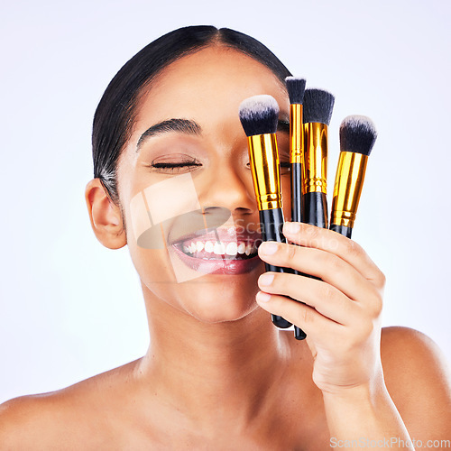 Image of Makeup brush, beauty and cosmetics of a happy woman in studio for skincare, self care and cosmetology. Skin glow, shine and wellness of a female model with facial application tools for foundation