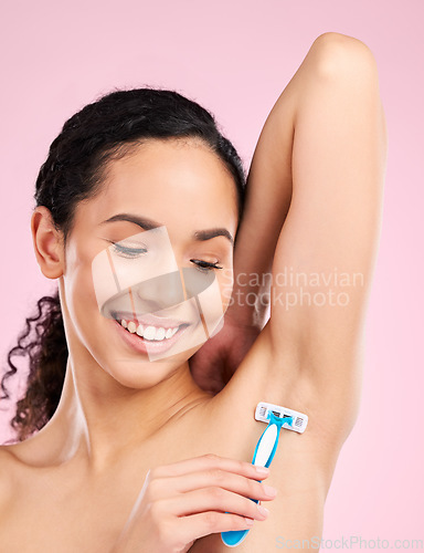 Image of Happy, armpit and a woman shaving for hair removal, beauty and care for body on a studio background. Smile, wellness and a young girl or model with a razor for grooming and hygiene on a backdrop