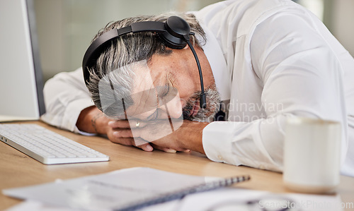 Image of Tired, customer service and male agent sleeping in his office while doing online consultation. Exhausted, burnout and mature man telemarketing or call center consultant taking a nap in the workplace.