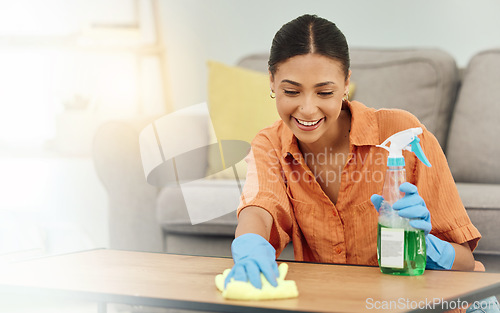 Image of Spray, woman and smile for cleaning table, furniture and housekeeping services at home. Female cleaner wipe surface with cloth, bottle of chemical product and disinfection of dust, bacteria and dirt