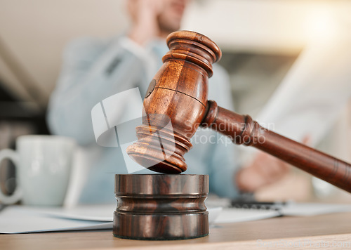 Image of Closeup, gavel and law on table, office and attorney man in blurred background with phone call for networking. Advocate, lawyer or judge with legal hammer, paperwork or documents for court evidence