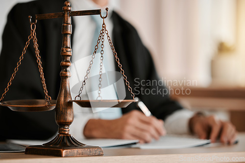 Image of Closeup, scales and law on table, office and attorney man in blurred background with reading for crime analysis. Advocate, lawyer or judge with legal hammer, paperwork or documents for court evidence