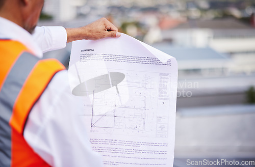 Image of Construction site, blueprint and man reading document of building proposal in city from the back. Closeup design of floor plan, project or architecture for industrial development in civil engineering