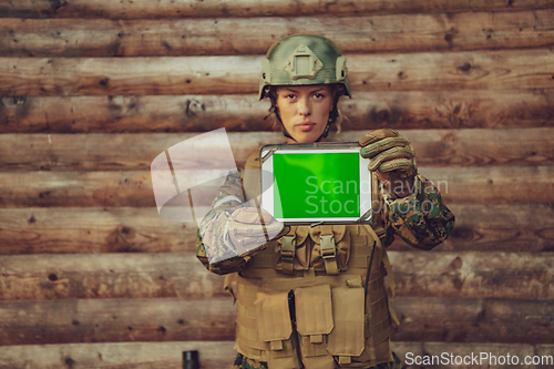 Image of Woman soldier using tablet computer against old wooden wall in camp