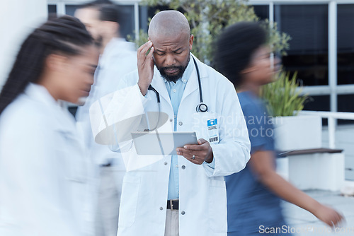 Image of Tablet, black man and doctor with stress in busy hospital, fatigue or burnout. Tech, medical professional or person with problem, crisis or challenge, headache or anxiety in mistake, fail or disaster