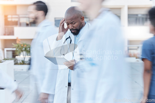 Image of Tablet, doctor and black man with headache in busy hospital, fatigue or burnout. Tech, medical professional or person with problem, crisis or challenge, stress or anxiety in mistake, fail or disaster