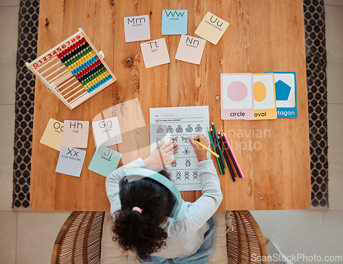 Image of Above, child and girl writing on table for homework or remote learning in home for development, growth and education. Kid, working and studying for school, math and writing on paper in living room