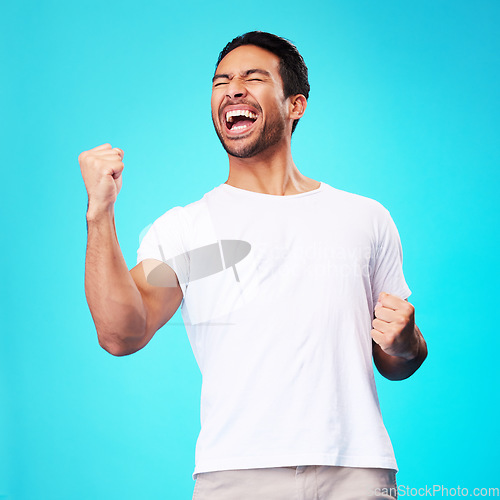 Image of Happy asian man, winner and fist in studio for celebration, achievement and success on blue background. Excited model shout to celebrate winning prize, deal and victory of lottery, reward and bonus