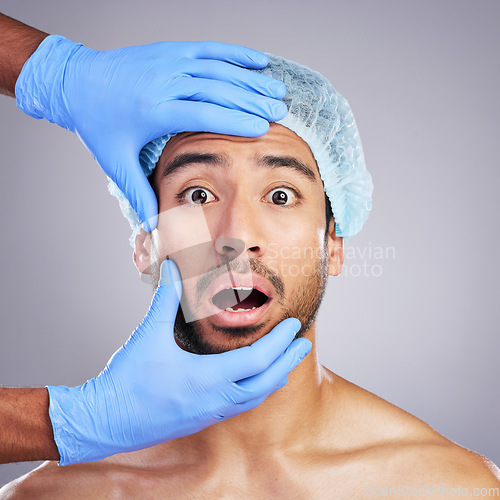 Image of Man, hands and face for plastic surgery in studio with fear, pain and scared for cosmetics by background. Doctor gloves, dermatology surgeon and patient with wow, surprise and facial transformation