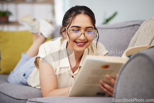 Image of Happy woman, reading and book on sofa in home for story, novel and studying literature. Young student, gen z girl and relax with books in lounge for learning, knowledge and education in living room