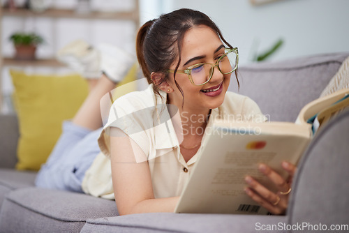 Image of Woman, sofa and reading book in living room for story, novel and learning knowledge. Happy female student, gen z girl and relax with books in lounge for studying, literature or hobby to enjoy at home