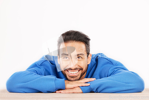 Image of Thinking, wonder and face of man on a white background with ideas, brainstorming and dream by table. Happy, mockup space and isolated male person resting on desk for choice or decision in studio