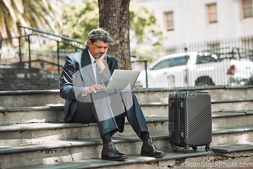 Image of Travel, email and businessman with laptop in the city for communication and booking a flight online. Serious, working and mature corporate manager with a computer and luggage for a ticket on the web