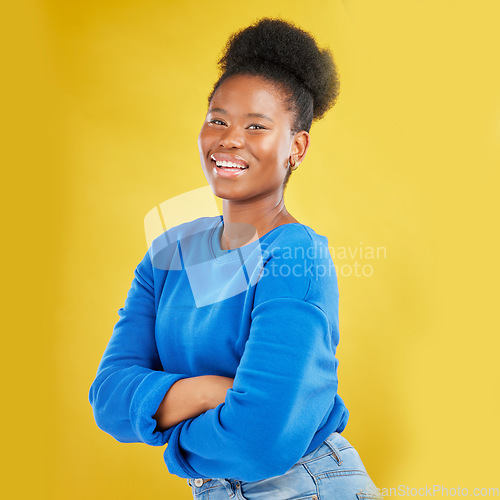 Image of Portrait, smile and arms crossed with a black woman on a yellow background in studio for fashion. Happy, confident and proud with a happy young person posing for trendy style in a clothes outfit