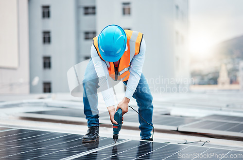 Image of Engineer man, drill and solar panel on roof with industry, sustainability or construction in city. Technician, power tools and photovoltaic system for building, development or renewable energy in cbd