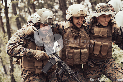 Image of Modern warfare military squad in battle action rescue wounded soldier help and support concept