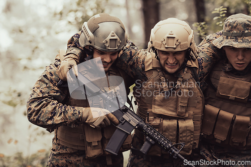 Image of Modern warfare military squad in battle action rescue wounded soldier help and support concept