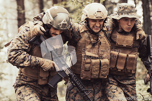 Image of Modern warfare military squad in battle action rescue wounded soldier help and support concept
