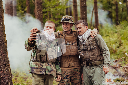 Image of Team of soldiers and terrorist taking selfie with smartphone in the forest