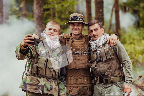 Image of Team of soldiers and terrorist taking selfie with smartphone in the forest