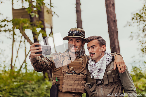 Image of Team of soldiers and terrorist taking selfie with smartphone in the forest