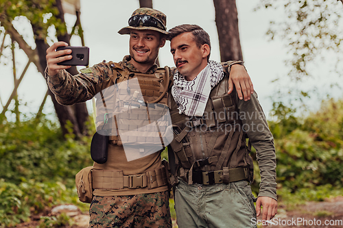 Image of Team of soldiers and terrorist taking selfie with smartphone in the forest