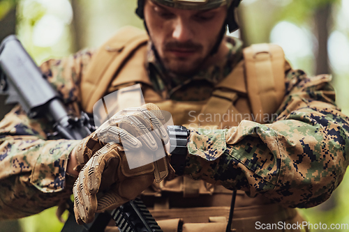 Image of American marine corps special operations soldier preparing tactical and commpunication gear for action battle closeup