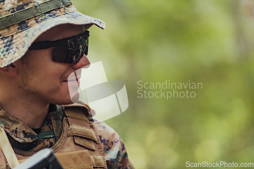 Image of Soldier portrait with protective army tactical gear and weapon having a break and relaxing